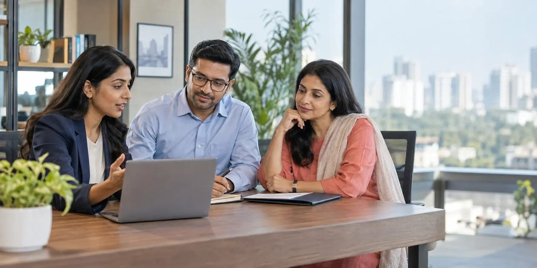 Three insurance brokerage colleagues reviewing policy details together on a laptop in a modern office